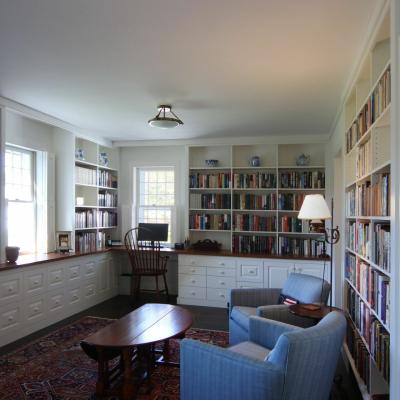 Cozy study with bookshelves, a lamp, and seating for reading.