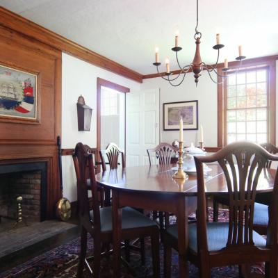 A dining room with a wooden table, chairs, fireplace, and wall art.