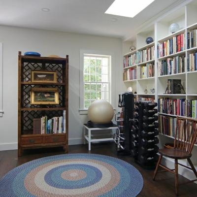 A bright home gym/library with bookshelves, a treadmill, and workout equipment.