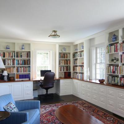 Cozy study featuring bookshelves, a desk, a chair, and a patterned rug.