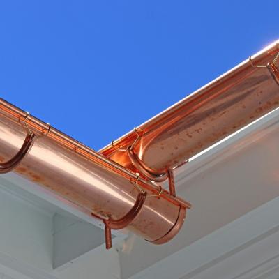 Close-up of copper gutters against a clear blue sky.