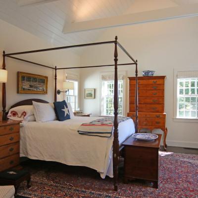 Cozy bedroom with a four-poster bed, vintage furniture, and large windows.