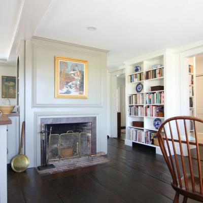Bright, cozy room featuring a fireplace, bookshelf, and dining table with wooden chairs.