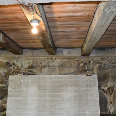 Interior view of a basement featuring wooden beams and stone walls.