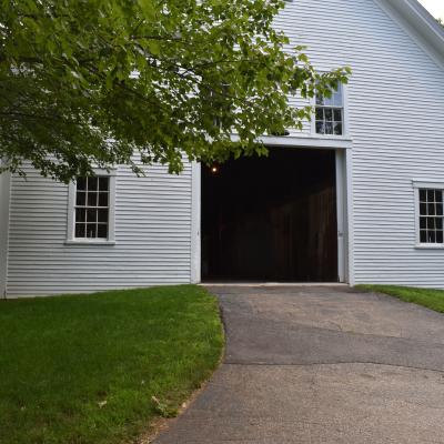 A white barn with an open doorway set in a green landscape.