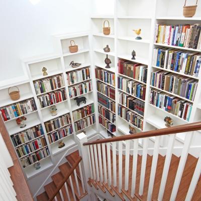 A white bookshelf staircase filled with books and decorative items.