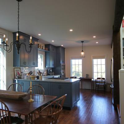 Cozy kitchen and dining area with wooden table, blue cabinets, and large windows.