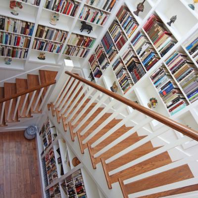Staircase leading down through a cozy library with bookshelves and decorative items.