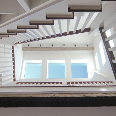 View from below a modern staircase with white railings and natural light streaming in.