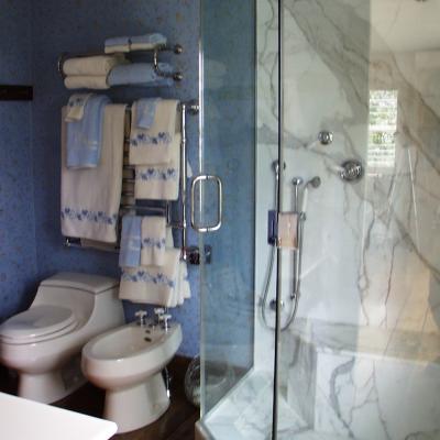 Modern bathroom featuring a glass shower, blue wallpaper, and decorative towels.