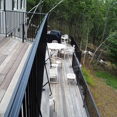 Deck with wooden furniture overlooking a green forested area.