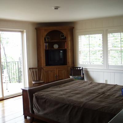 Cozy bedroom with a bed, wooden furniture, and large windows opening to a balcony.