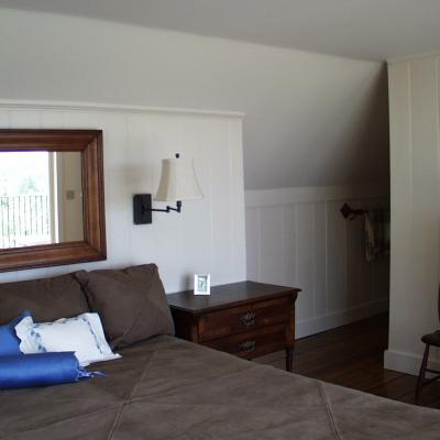 Cozy bedroom with a brown bed, wooden furniture, and a large mirror reflecting natural light.