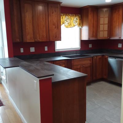 Bright kitchen with wooden cabinets, a gray countertop, and a red accent wall.