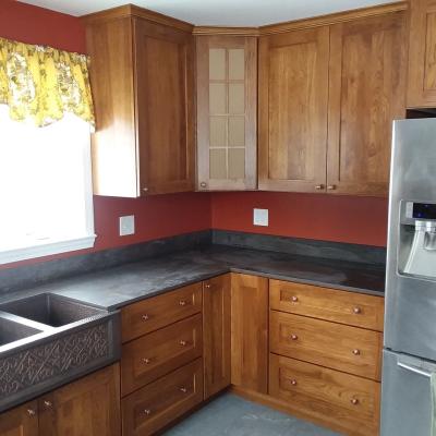 Modern kitchen with wooden cabinets, black countertops, and a dual sink under a window.
