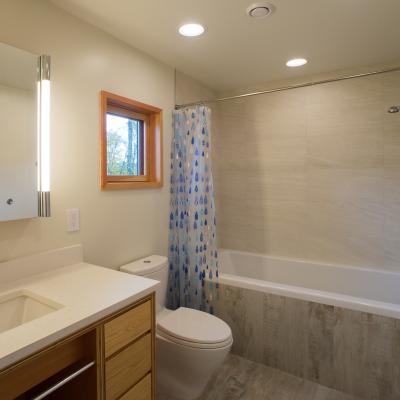 Modern bathroom with a bathtub, shower, sink, and window with natural light.
