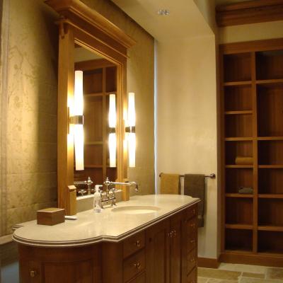 Modern bathroom with wooden vanity, mirror, and soft lighting. Neat shelving in the background.