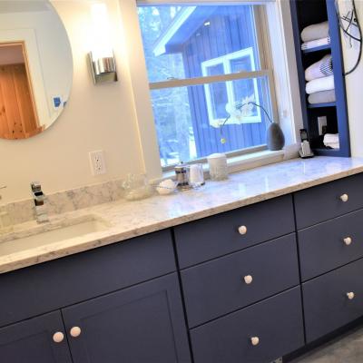 Modern bathroom vanity with marble countertop, circular mirror, and neatly arranged decor.