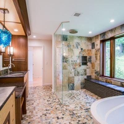 Luxurious modern bathroom with a glass shower, soaking tub, and natural light from windows.