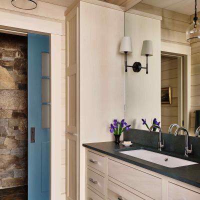 Bright bathroom features a dark countertop, sink, and purple flowers by the mirror.
