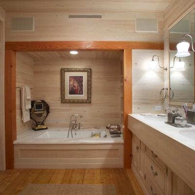 Modern bathroom with wood-paneled walls, a bathtub, and dual sinks.