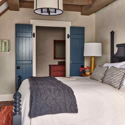 Cozy bedroom with a bed, patterned pillows, and blue shuttered doorway.
