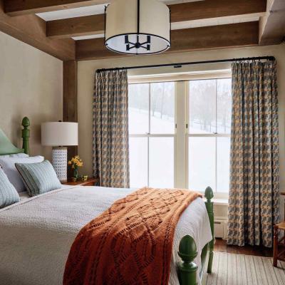 Cozy bedroom featuring a green bed, patterned curtains, and snow view outside.