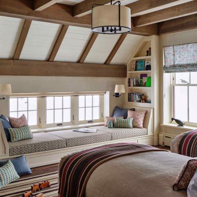 Cozy bedroom with a window seat, bookshelves, and warm wooden beams.