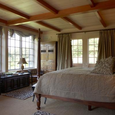 Cozy bedroom with large windows, a four-poster bed, and wooden details.