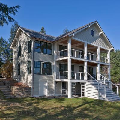 Stylish multi-level house with a porch, surrounded by trees and blue sky.