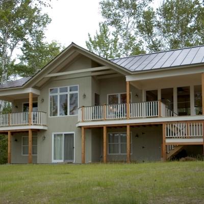 Contemporary two-story house with decks, surrounded by trees and grassy area.