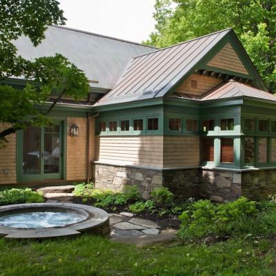 A stylish home exterior with a stone hot tub and lush greenery surrounding it.