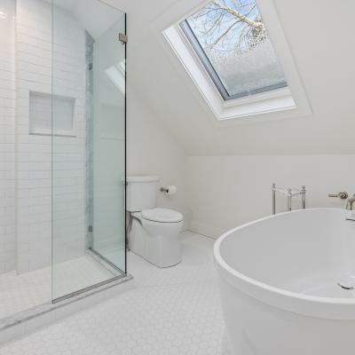 Modern bathroom with a glass shower, freestanding tub, and skylight.