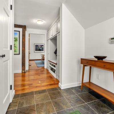 Bright entryway featuring a wooden console table and tile flooring, leading to a cozy living area.