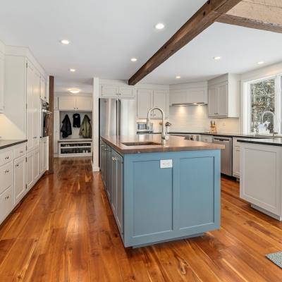 Modern kitchen featuring blue island, white cabinets, and hardwood floors.