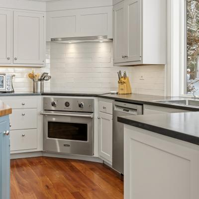 Modern kitchen with stainless steel appliances, white cabinetry, and a view of snow outside.