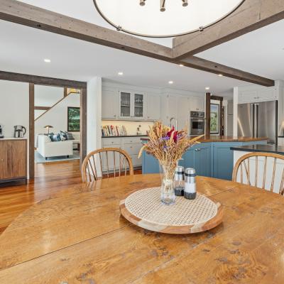 Bright kitchen with wooden accents, a round table, and a view of a cozy living area.