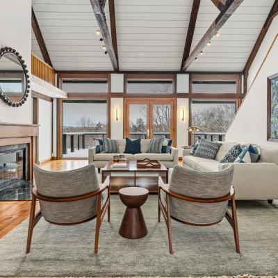 Modern living room with large windows, cozy seating, and a spiral staircase.