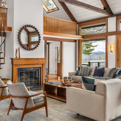 Modern living room with spiral staircase and large windows overlooking mountains.