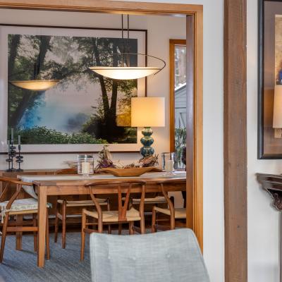 Interior view of a dining area with wood furniture, plants, and decorative artwork.