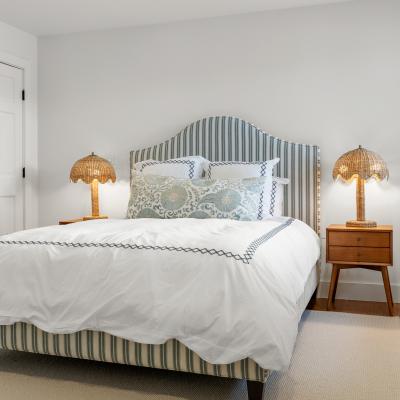 Modern bedroom with a striped bed, decorative pillows, and stylish nightstands.