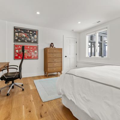 Bright bedroom with a desk, chair, dresser, and colorful wall art.