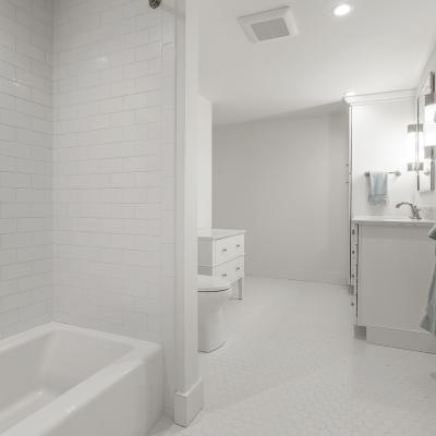 Bright, modern bathroom with a tub, white tile, and light fixtures.