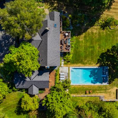 Aerial view of a house with a pool surrounded by greenery and landscaped gardens.