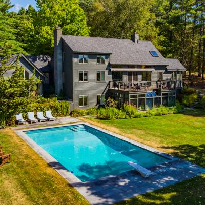 A spacious house with a pool, surrounded by green grass and trees.