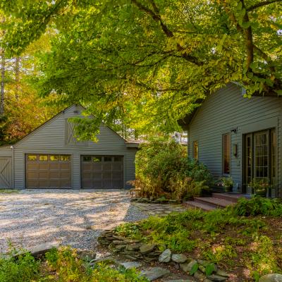 A cozy gray house and garage surrounded by vibrant trees and landscaping.