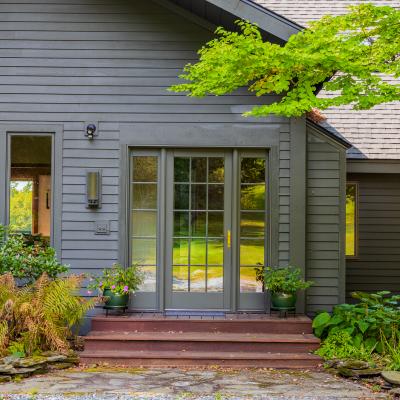 Front entrance of a modern house with green foliage and steps.