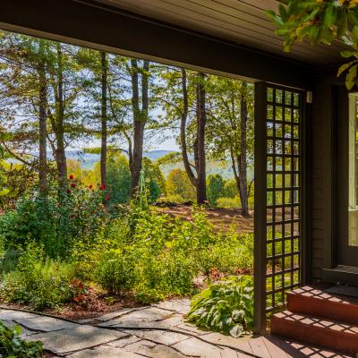 View of a garden with flowers and trees, framed by a porch entrance.