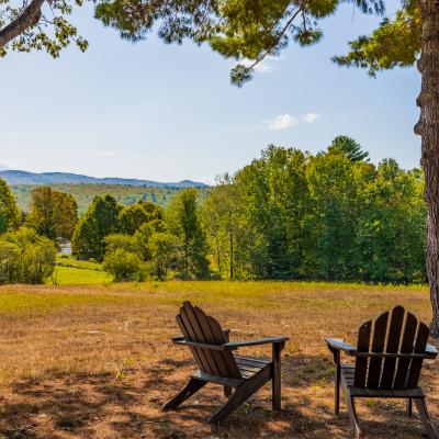 Two wooden chairs overlook a scenic green landscape and distant mountains under a clear sky.