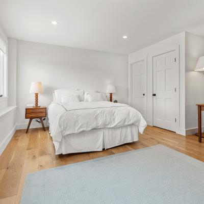 Bright, modern bedroom with a bed, nightstand, desk, and large windows.